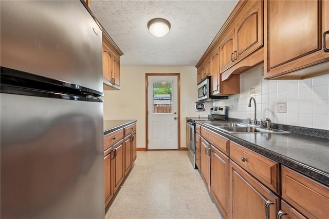 211 Old Meadow Dr, Hempfield Twp Wml, PA 15601 - kitchen featuring stainless steel appliances, a sink, dark countertops, brown cabinetry, and a textured ceiling