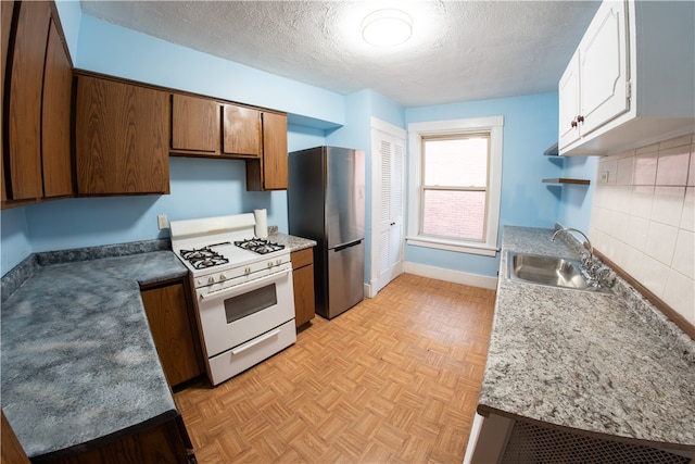 222-224 Alice St, Mount Oliver, PA 15210 - kitchen with white range with gas cooktop, a sink, freestanding refrigerator, a textured ceiling, and baseboards