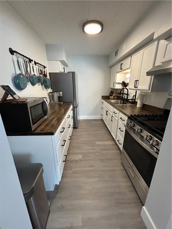 1326 6th Ave Unit 401, Beaver Falls, PA 15010 - kitchen with appliances with stainless steel finishes, wooden counters, a sink, white cabinets, and under cabinet range hood