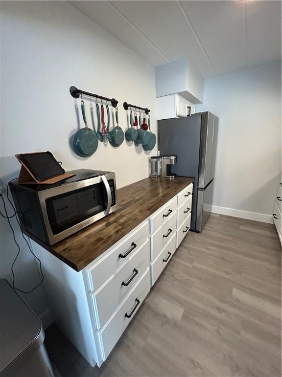 1326 6th Ave Unit 401, Beaver Falls, PA 15010 - kitchen featuring butcher block counters, stainless steel appliances, light wood-style flooring, white cabinetry, and baseboards