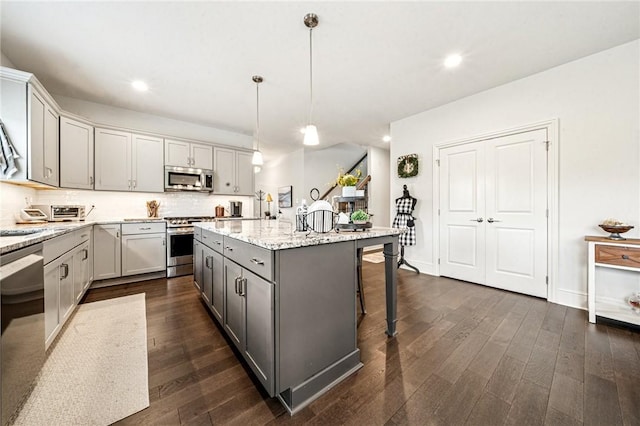 137 Summer Ln, Mount Pleasant Twp Was, PA 15057 - kitchen featuring appliances with stainless steel finishes, gray cabinets, a kitchen island with sink, a breakfast bar, and backsplash