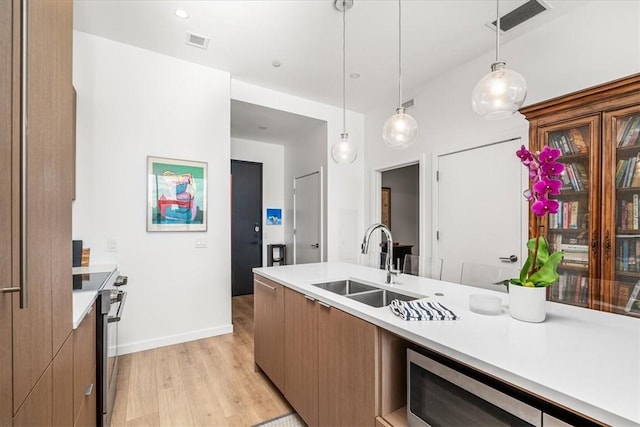 2554 Smallman St Unit 406, Downtown Pgh, PA 15222 - kitchen with a sink, light countertops, light wood-style flooring, decorative light fixtures, and appliances with stainless steel finishes