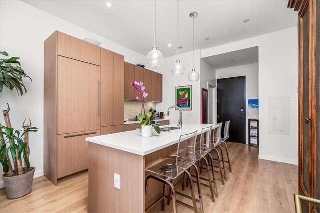 2554 Smallman St Unit 406, Downtown Pgh, PA 15222 - kitchen with a sink, light wood finished floors, light countertops, a center island with sink, and a kitchen breakfast bar