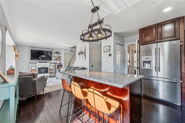 536 Cherryhill Dr, Cecil, PA 15017 - kitchen featuring stainless steel fridge with ice dispenser, dark wood-style floors, a breakfast bar area, a glass covered fireplace, and recessed lighting