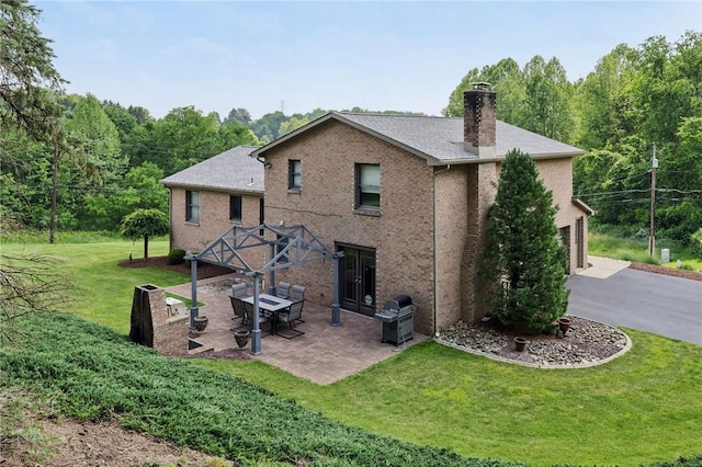 100 Welty Dr, Allegheny Twp Wml, PA 15068 - back of property featuring a chimney, a yard, a garage, asphalt driveway, and a patio