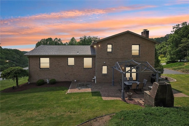 100 Welty Dr, Allegheny Twp Wml, PA 15068 - back of property at dusk with a patio, a lawn, brick siding, and a chimney