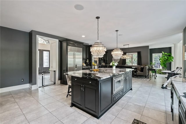 623 Oswego Dr, Adams Twp, PA 15044 - kitchen featuring dark cabinets, light stone counters, a chandelier, open floor plan, and light tile patterned floors