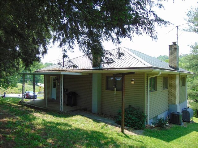 822 Fayette City Rd, Washington Twp, PA 15438 - back of property with a lawn, central AC unit, a chimney, and metal roof