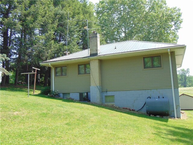 822 Fayette City Rd, Washington Twp, PA 15438 - back of property featuring oil tank, a chimney, a yard, and metal roof