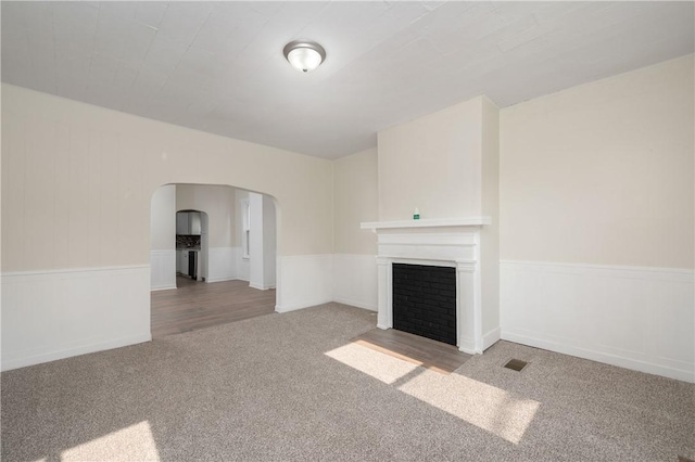 330 N Elm St, City Of But Nw, PA 16001 - unfurnished living room with carpet floors, arched walkways, a fireplace with flush hearth, and a wainscoted wall