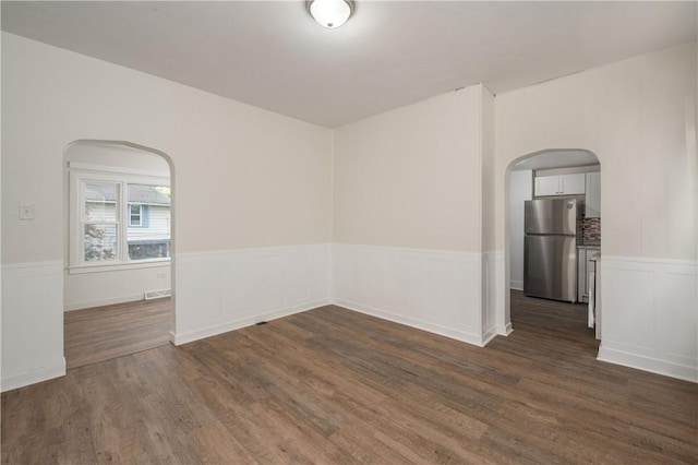 330 N Elm St, City Of But Nw, PA 16001 - unfurnished room with arched walkways, a wainscoted wall, and dark wood-type flooring