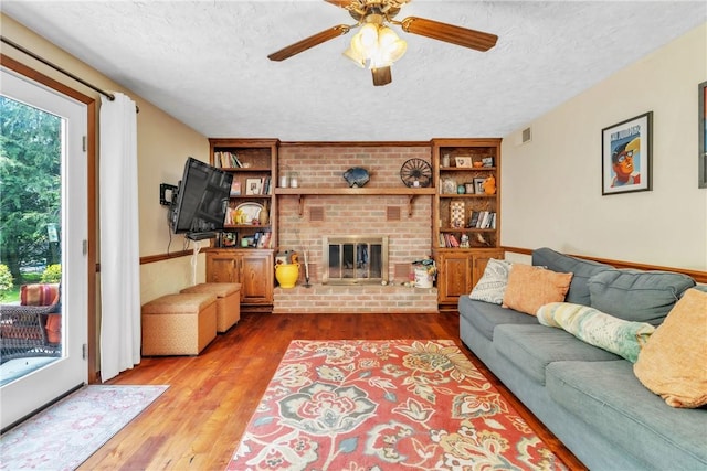 106 Shawnee Dr, Center Twp But, PA 16001 - living area featuring a textured ceiling, wood finished floors, ceiling fan, a fireplace, and built in features