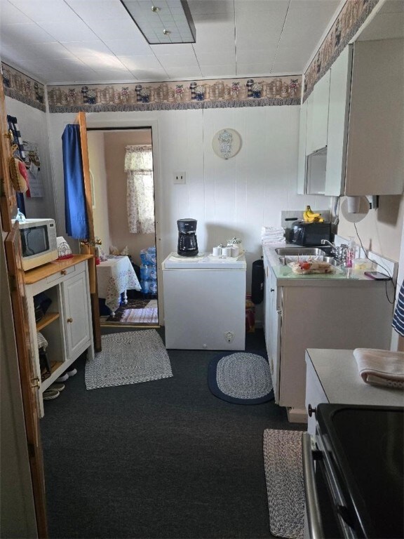 114 Dry Knob Rd, Georges Twp, PA 15478 - kitchen with white microwave, a sink, carpet, stainless steel range, and light countertops