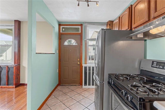 1913 Saint Paul St, South Side, PA 15203 - kitchen with stainless steel gas range oven, under cabinet range hood, brown cabinets, baseboards, and light tile patterned floors