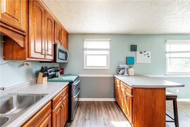 1941 Ivanhoe Dr, North Huntingdon, PA 15642 - kitchen with stainless steel appliances, a sink, a peninsula, a kitchen bar, and brown cabinets