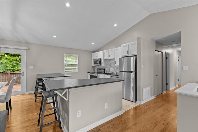 509 Cresthaven Dr, Plum Boro, PA 15239 - kitchen featuring appliances with stainless steel finishes, a kitchen island, light wood-type flooring, vaulted ceiling, and plenty of natural light
