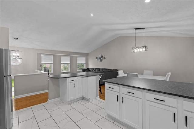 509 Cresthaven Dr, Plum Boro, PA 15239 - kitchen with freestanding refrigerator, dark countertops, lofted ceiling, white cabinets, and a chandelier