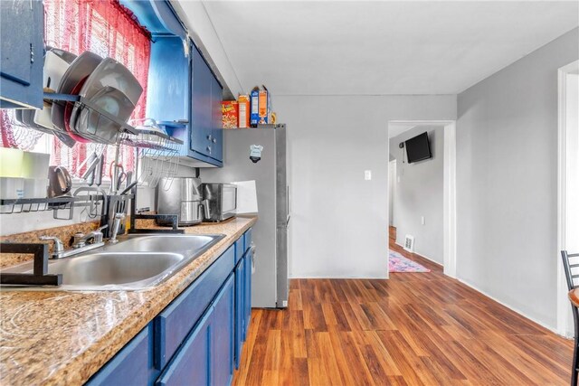 439 Ford St, West Mifflin, PA 15122 - kitchen featuring blue cabinets, wood finished floors, healthy amount of natural light, and freestanding refrigerator