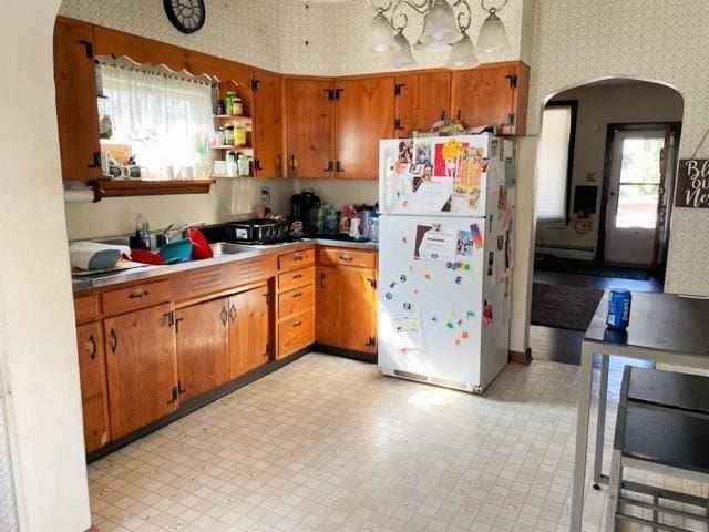 22 Lemon St, Uniontown, PA 15401 - kitchen featuring freestanding refrigerator, wallpapered walls, arched walkways, brown cabinets, and plenty of natural light