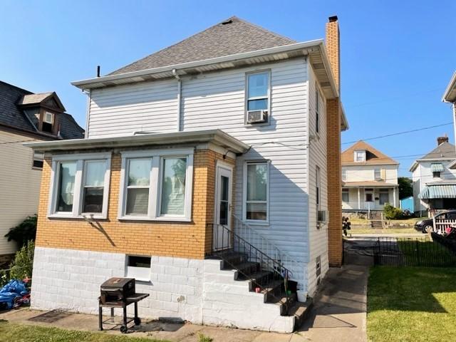 22 Lemon St, Uniontown, PA 15401 - back of property with entry steps, a chimney, brick siding, and cooling unit