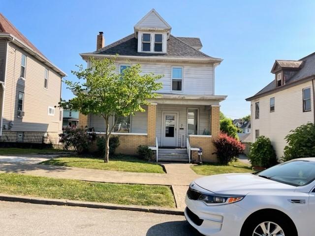 22 Lemon St, Uniontown, PA 15401 - traditional style home with brick siding, a porch, a chimney, and a front lawn