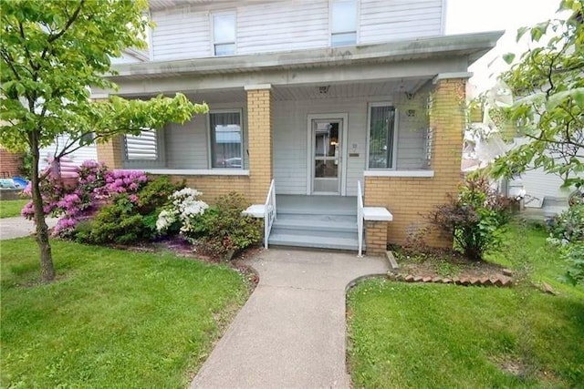 22 Lemon St, Uniontown, PA 15401 - view of front of home with brick siding, covered porch, and a front yard
