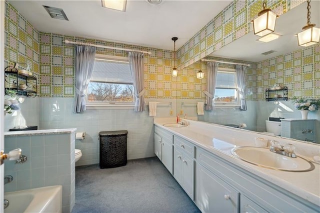 229 Crawford Ln, Rostraver, PA 15012 - full bathroom featuring toilet, double vanity, a tub, tile walls, and wallpapered walls