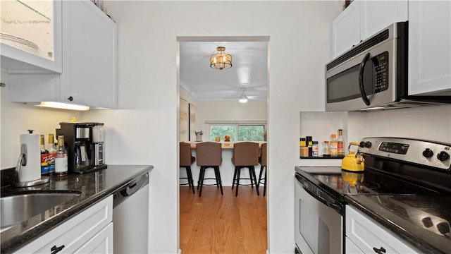 718 Carriage Cir, Pennsbury, PA 15205 - kitchen featuring stainless steel appliances, white cabinetry, ceiling fan, light wood-type flooring, and dark stone countertops