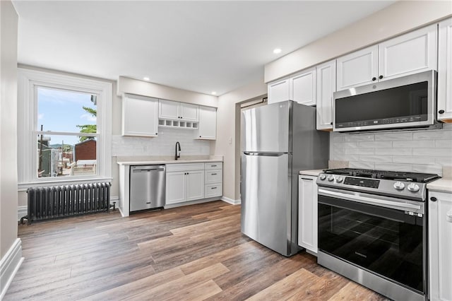 130 Pearl St, Bloomfield, PA 15224 - kitchen with appliances with stainless steel finishes, radiator heating unit, light countertops, light wood finished floors, and recessed lighting