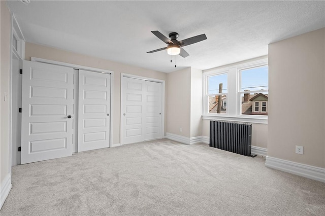 130 Pearl St, Bloomfield, PA 15224 - unfurnished bedroom featuring multiple closets, radiator heating unit, carpet flooring, baseboards, and a ceiling fan