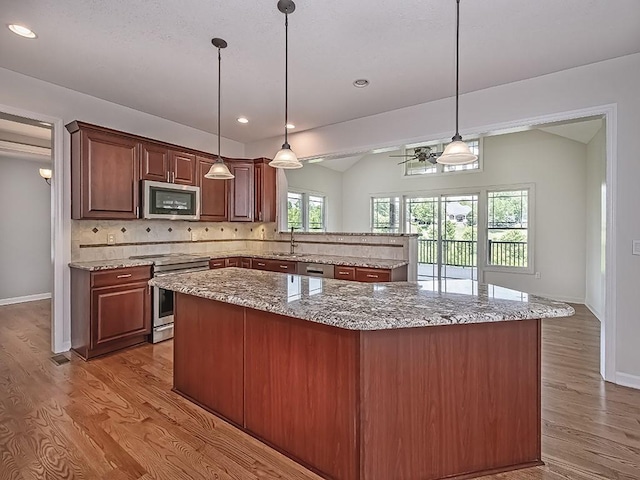 430 Longleaf Dr, Peters Twp, PA 15367 - kitchen with stainless steel appliances, a center island, backsplash, light wood-type flooring, and baseboards