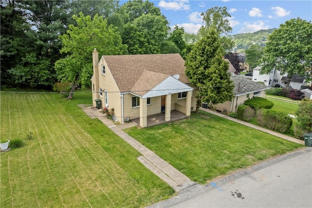 2396 Foster Rd, White Oak, PA 15131 - view of front of house with a chimney, a front yard, brick siding, and a patio area