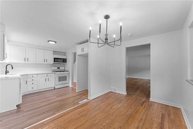 2396 Foster Rd, White Oak, PA 15131 - kitchen with white appliances, a chandelier, a sink, white cabinets, and light countertops