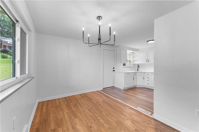 2396 Foster Rd, White Oak, PA 15131 - unfurnished dining area with a chandelier, light wood-style floors, a sink, and baseboards