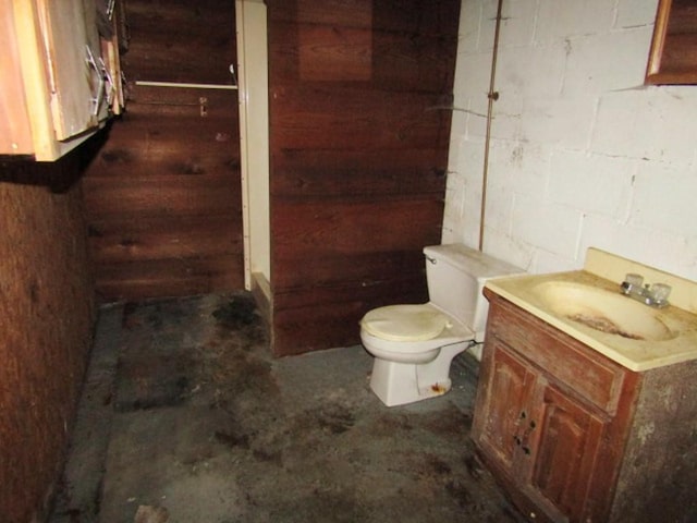 945 Roup Ave, Brackenridge, PA 15014 - bathroom featuring vanity, toilet, concrete block wall, unfinished concrete flooring, and wood walls