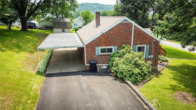 145 7th St, E Butler Boro, PA 16029 - view of front facade with asphalt driveway, a carport, brick siding, a chimney, and a front yard