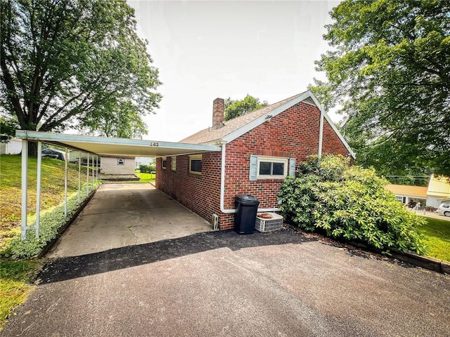 145 7th St, E Butler Boro, PA 16029 - view of home's exterior with brick siding, a chimney, driveway, and a carport