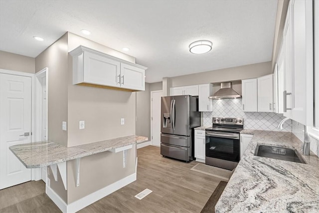 14 Laurel Hill Rd, Cecil, PA 15057 - kitchen featuring appliances with stainless steel finishes, a sink, wall chimney exhaust hood, light stone countertops, and light wood-style flooring