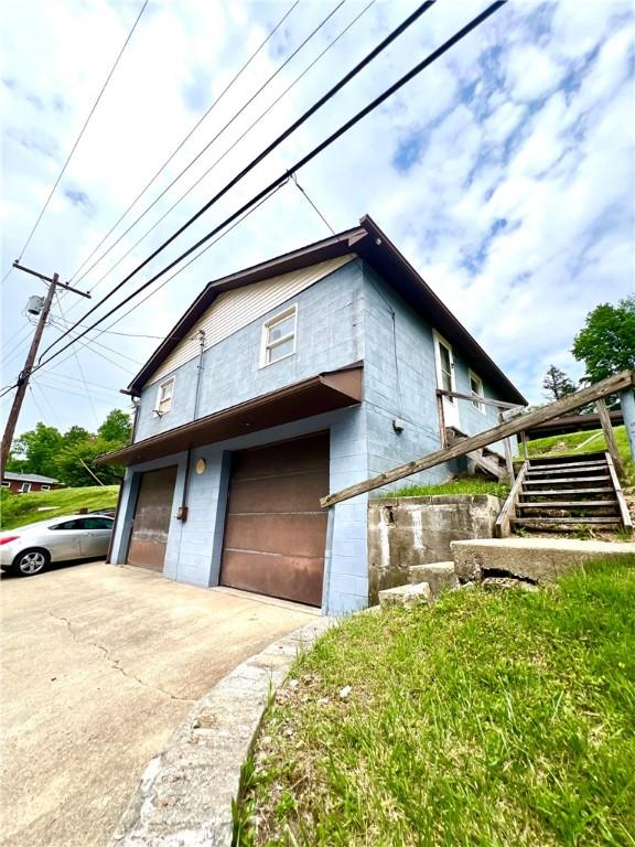 1464 State Route 819, Salem Twp Wml, PA 15601 - view of side of home with concrete block siding, a garage, and driveway