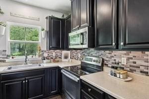 139 Moyer Hl, Cranberry Twp, PA 16066 - kitchen with stainless steel appliances, light countertops, tasteful backsplash, and dark cabinetry