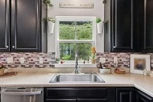 139 Moyer Hl, Cranberry Twp, PA 16066 - kitchen with stainless steel dishwasher, a sink, dark cabinetry, light countertops, and tasteful backsplash