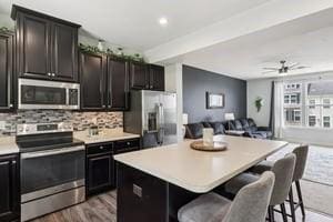 139 Moyer Hl, Cranberry Twp, PA 16066 - kitchen featuring appliances with stainless steel finishes, open floor plan, decorative backsplash, light countertops, and a breakfast bar
