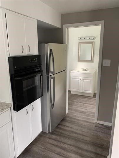 551-555 New Alexandria Rd, Hempfield Twp Wml, PA 15601 - kitchen featuring freestanding refrigerator, black oven, dark wood-type flooring, and white cabinets