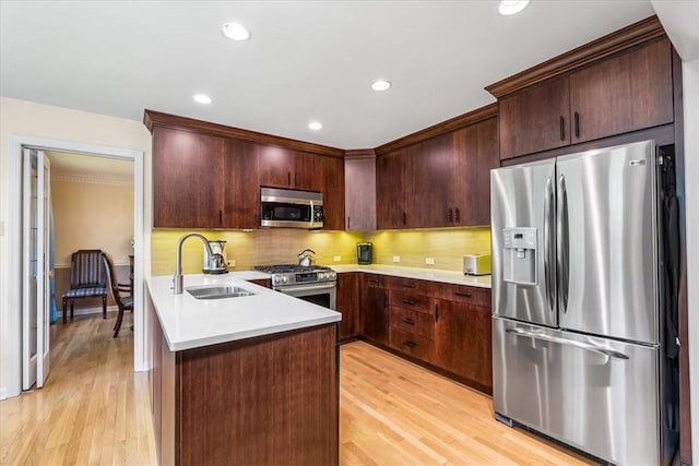 8963 Seneca Ave, Mccandless, PA 15237 - kitchen featuring appliances with stainless steel finishes, a sink, a peninsula, light wood-style floors, and backsplash