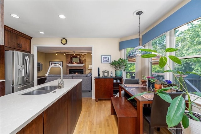 8963 Seneca Ave, Mccandless, PA 15237 - kitchen with stainless steel refrigerator with ice dispenser, a sink, a brick fireplace, light countertops, and light wood finished floors