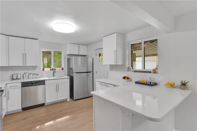 9830 Don Dr, North Huntingdon, PA 15642 - kitchen with appliances with stainless steel finishes, a sink, a peninsula, light countertops, and white cabinetry