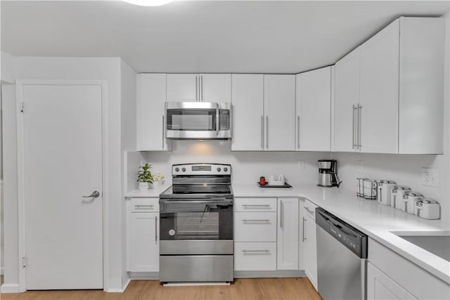 9830 Don Dr, North Huntingdon, PA 15642 - kitchen with appliances with stainless steel finishes, light wood-style floors, light countertops, and white cabinets