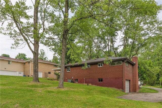9830 Don Dr, North Huntingdon, PA 15642 - rear view of house with an attached garage, a lawn, a chimney, central AC unit, and asphalt driveway