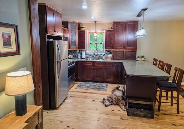 277 Dunn Rd, Hempfield Twp Wml, PA 15601 - kitchen featuring stainless steel appliances, a peninsula, reddish brown cabinets, a sink, and a kitchen bar