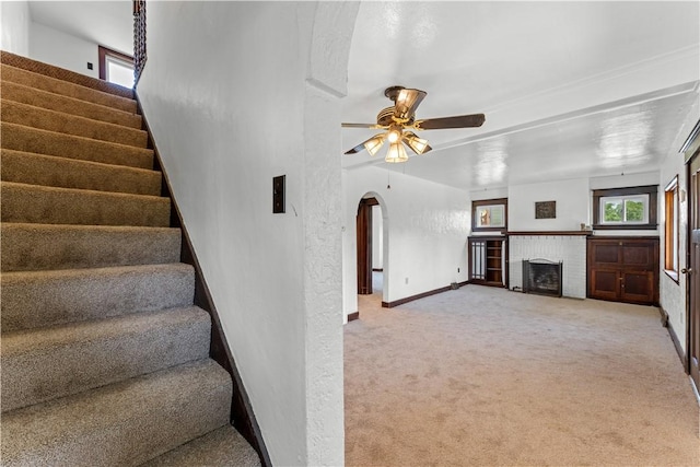 707 Hamil Rd, Penn Hills, PA 15147 - unfurnished living room featuring light colored carpet, stairway, arched walkways, a ceiling fan, and a fireplace